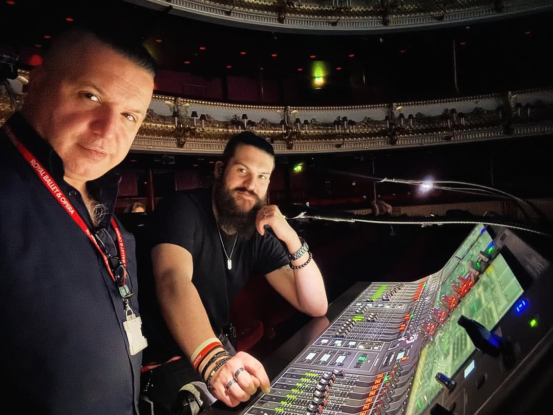 the image shows two sound engineers smiling at the camera behind the control desk at the royal opera house